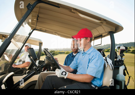 Männer fahren Golfcarts auf Golfplatz Stockfoto