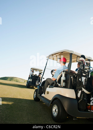 Männer fahren Golfcarts auf Golfplatz Stockfoto