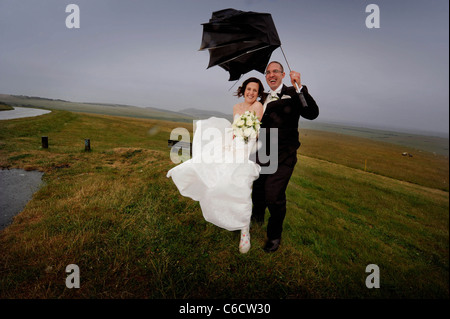 Der strömende Regen dämpft die Hochzeit des glücklichen Paares Sandra und Scott nicht, da sie bei starkem Wind auf Beachy Head posieren. Stockfoto