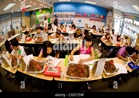 Hispanic und asiatisch-amerikanische Studenten der Naturwissenschaften, jeweils mit ihrem Modell eines Vulkans teilnehmen in einem Sommer-Learning-Programm. Stockfoto