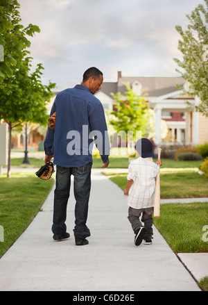 Vater und Sohn zu Fuß mit Baseball-Handschuh und Fledermaus Stockfoto