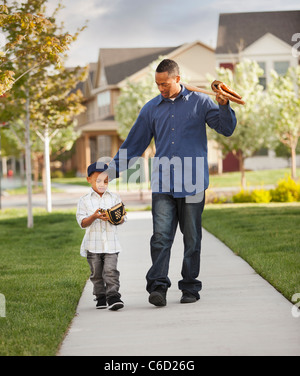 Vater und Sohn zu Fuß mit Baseball-Handschuh und Fledermaus Stockfoto