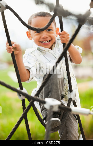 Gemischte Rassen junge Klettern auf Spielplatz Stockfoto