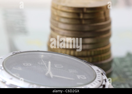 Zeit ist Geld - Uhr vor Haufen von Euro-Münzen Stockfoto