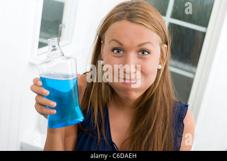 Junge Frau mit Mund voll von blauen Mundwasser Stockfoto