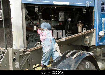 Ein "Dummy" gekleidet wie ein kleines Kind, die Festsetzung eines LKW-Motors zeigt das Dummy mit einem Schraubenschlüssel und Details des Motorraums Stockfoto