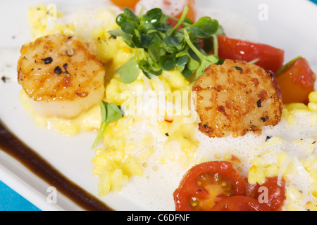 Safran-Risotto mit gegrillten Jakobsmuscheln und Cherry-Tomaten-sauce Stockfoto