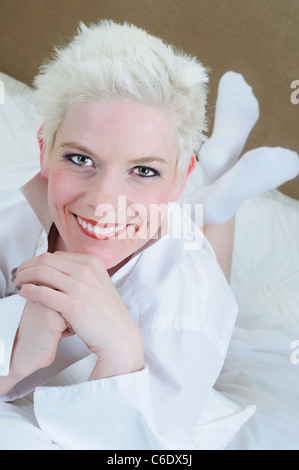 Nahaufnahme von einer schönen Frau mit kurzen blonden Haaren im Bett liegend Stockfoto