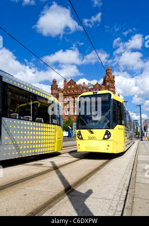 Zwei moderne gelbe Metrolink Straßenbahnen übergeben einander zwischen quadratischen Stationen im Zentrum von Manchester Deansgate und St. Peter Stockfoto