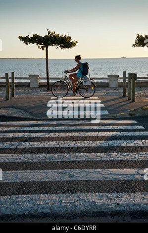 Der Strand bei Saint Georges De Didonne, Charente-Maritime, Frankreich.  Radfahrer fährt entlang der Strandpromenade in der Nähe von einem Zebrastreifen Stockfoto