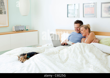 Paar mit Laptop zusammen im Bett Stockfoto