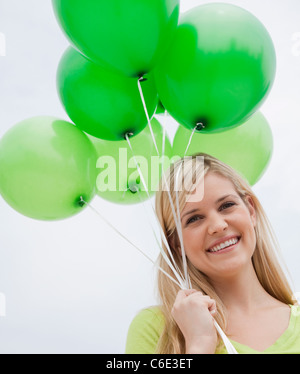 USA, New Jersey, Jersey City, Porträt der jungen Frau mit grünen Ballons Stockfoto
