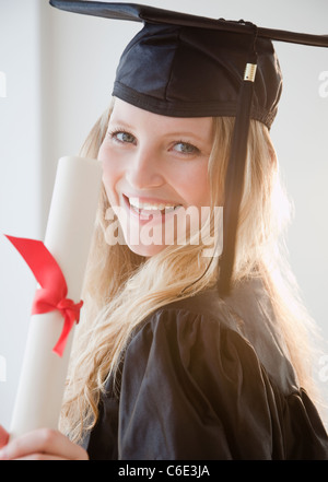 USA, New Jersey, Jersey City, junge Frau trägt Graduierung Kleid mit Diplom Stockfoto