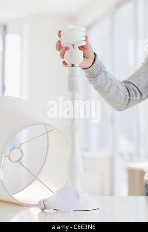 USA, New Jersey, Jersey City, Frau wechselnden klassischen Glühbirne Energie effiziente Lampe Stockfoto