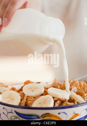USA, New Jersey, Jersey City, Nahaufnahme von Hand Gießen Milch in Schüssel mit Müsli Stockfoto