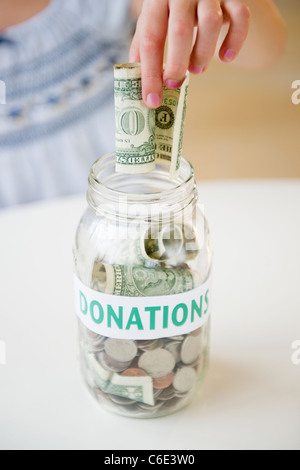 USA, New Jersey, Jersey City, Nahaufnahme des Mädchens Hand Dollarschein in Glas setzen Stockfoto