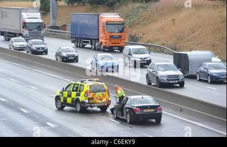 EIN HIGHWAYS AGENCY TRAFFIC OFFICER KÜMMERT SICH UM EIN GESTRANDETES AUTOFAHRER AUF DER ÜBERHOLSPUR DER M6 AUTOBAHN NACH EINEM CRASH-UK Stockfoto