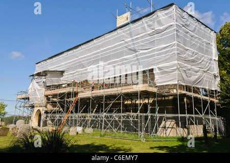 Alte Dorfkirche restauriert.  Umgeben von Gerüsten und bedeckt mit Kunststoff-Folie Stockfoto