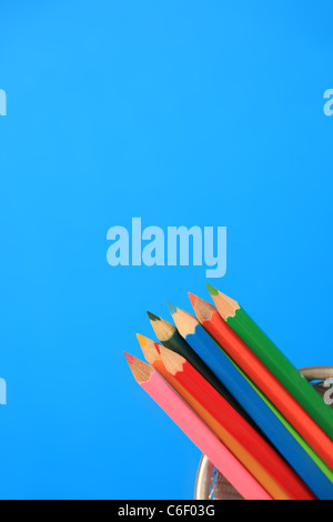 Multi farbige Stifte in einem Topf, blauen Hintergrund. Stockfoto