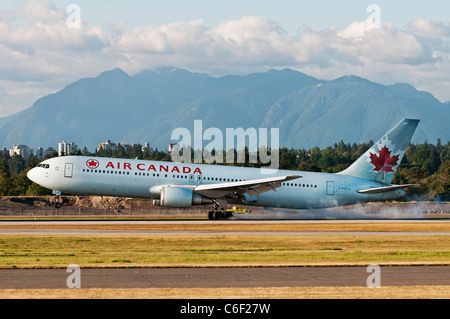 Ein Air Canada Boeing 767 (767-300ER) landet auf dem Flughafen Vancouver International Airport. Die North Shore Mountains bilden eine malerische Kulisse. Stockfoto