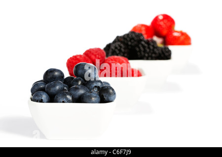 Heidelbeeren in einer Schüssel mit anderen wilden Beeren im Hintergrund auf weißem Hintergrund Stockfoto