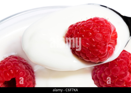 Nahaufnahme von einer Himbeere auf einem Löffel mit Joghurt oben von anderen Himbeeren in einem dessert Stockfoto