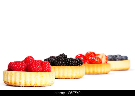 Himbeeren in Törtchen Kuchen vor anderen Törtchen Kuchen mit Waldbeeren auf weißem Hintergrund Stockfoto