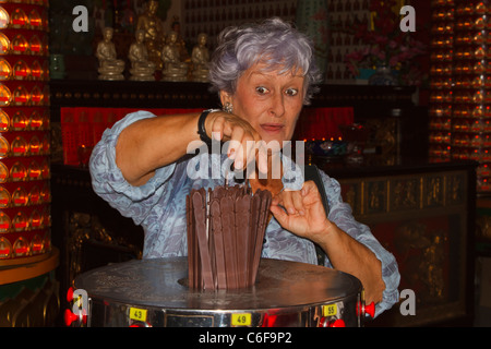 Eine ältere Frau mit Kau Cim, Wahrsagen Stöcke in den chinesischen Thean Hou Tempel, Kuala Lumpur, Malaysia. Stockfoto