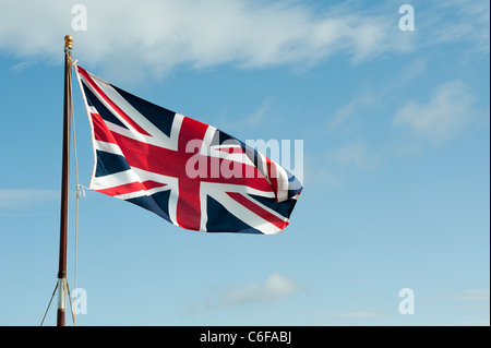 Union Jack Flagge im Wind knattern vor blauem Himmel Stockfoto