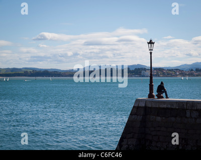 Einen nachdenklichen jungen sitzen auf der Anklagebank, Blick auf das Meer Stockfoto