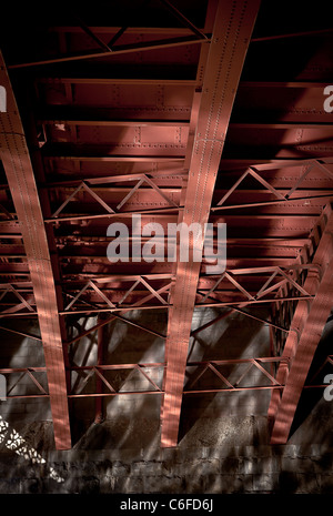 Rote Stahlträger unter einer Brücke mit Reflexionen Stockfoto