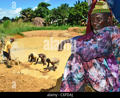 Mann in bunten lila Kleidung betreut eine Diamantenmine bei Kono, Sierra Leone, Westafrika Stockfoto