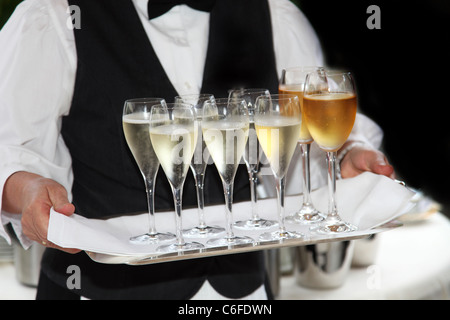 Kellner serviert Sekt und Wein - im Vordergrund sind die Wein und Champagner - Gläser auf ein Tablett zu sehen. Stockfoto