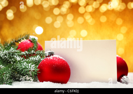 Nahaufnahme der Weihnachtskugeln, leere Karte und Tannenzweig auf festlichen Hintergrund. Stockfoto