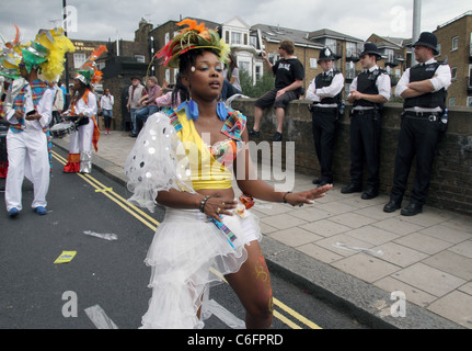 Nachtschwärmer und Tänzer in Tracht vorbei an Polizisten in Notting Hill Carnival, London, UK Stockfoto