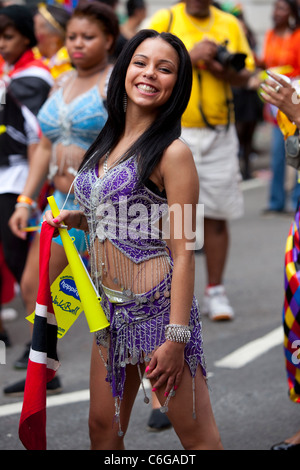 Eine junge Tänzerin, die beim Notting Hill Carnival in London, England, Großbritannien posiert und lächelt. Stockfoto