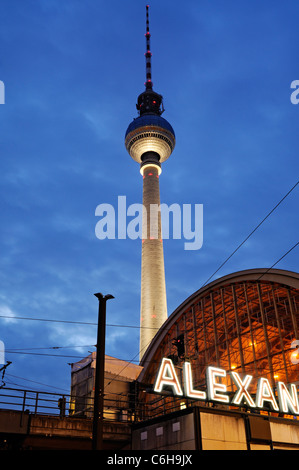 Nachtaufnahme vom Bahnhof Berlin Alexanderplatz mit dem berühmten Fernsehturm im Hintergrund. Stockfoto