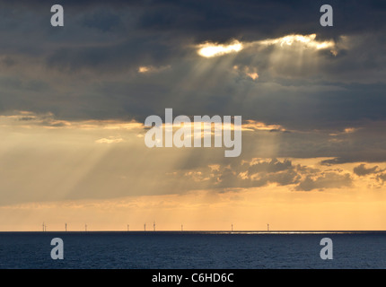 Strahlen von der späten Nachmittagssonne scheint durch Wolken auf einen Offshore-Windpark in Deutschland Stockfoto