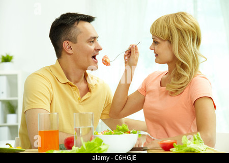 Bild der Frau, die ihrem Ehemann Scheibe Tomate auf Gabel Stockfoto