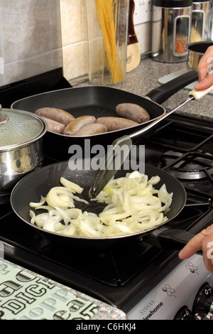 Zwiebeln gebraten in der Pfanne mit Würstchen Kochen im Hintergrund Stockfoto