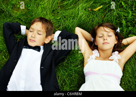 Porträt der ruhige Kinder Braut und Bräutigam liegen auf dem grünen Rasen Stockfoto