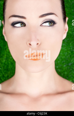 Closeup Portrait einer schönen verdächtige Frau wegschauen im Studio gegen green Stockfoto