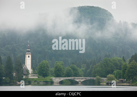 Kirche und Brücke bei Ribcev Laz an einem nebligen Morgen, See Bohinj, Slowenien. Stockfoto