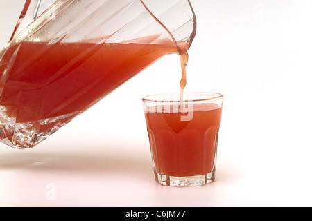 Gießen ein Glas frisch gepressten rosa Grapefruitsaft auf weißem Hintergrund Stockfoto