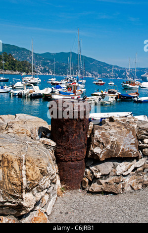 Eine rostige Kanonenrohr fungiert als eine attraktive Strebepfeiler an einer Felswand vor Boote auf einem blauen Meer schwimmen Santa Margherita Stockfoto