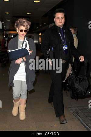 Kelly Osbourne scheint eine böse Verletzungen erlitten haben, nachdem sie am Londoner Flughafen Heathrow mit dem rechten Arm in gerissen wurde Stockfoto