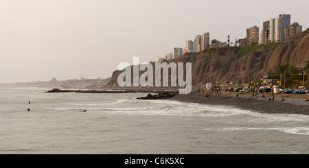 Touristen am Strand mit einer Stadt im Hintergrund, Miraflores District, Provinz Lima, Peru Stockfoto