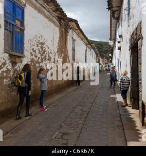 Mädchen unter Bild ihrer Schwester in einer Straße von Barrio de San Blas, Cuzco, Peru Stockfoto