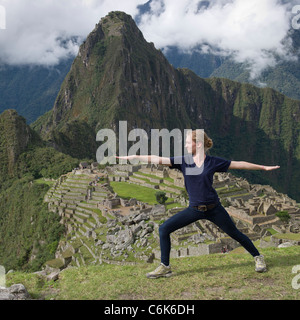 Junges Mädchen tun Krieger 2 Pose mit Die verlorene Stadt der Inkas im Hintergrund, Machu Picchu, Cusco Region, Peru Stockfoto