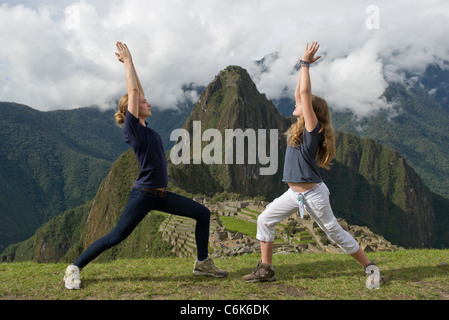 Teenage Mädchen tun, Krieger 1 Pose mit Die verlorene Stadt der Inkas im Hintergrund, Machu Picchu, Cusco Region, Peru Stockfoto